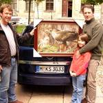 Paschalis Dougalis (rechts) mit seiner Tochter überreicht Detlef Becker eines seiner Bilder.