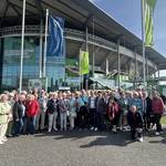 Gruppenfoto der Teilnehmerinnen und Teilnehmer der ersten Bürgerfahrt vor der Volkswagen Arena